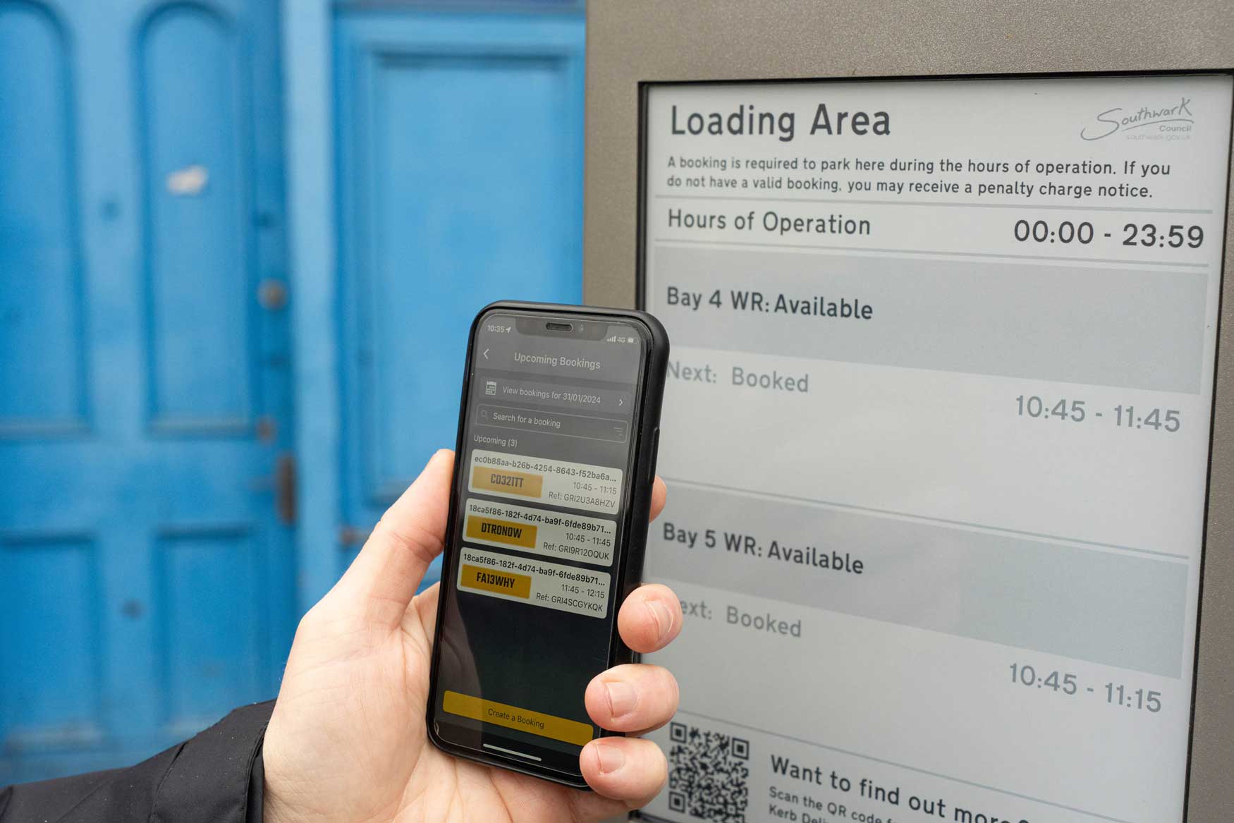 Driver checking their booking in the Kerb mobile application, on street by a smart sign